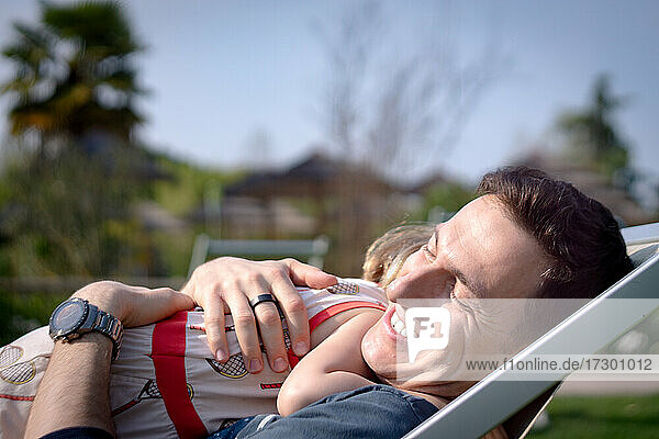Young girl hugging her father while sitting in lounge chair in park