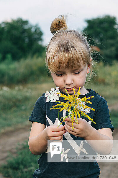 cute little girl holding wildflowers in her hands