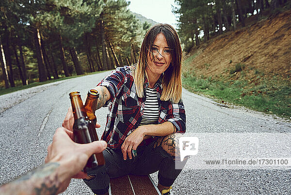 Eine Frau auf einem Skateboard stößt mit einem Bier an