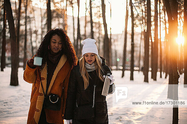 Freundinnen spazieren im Park bei Sonnenuntergang im Winter