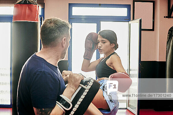 Young woman training with her Muay Thai trainer in a gym