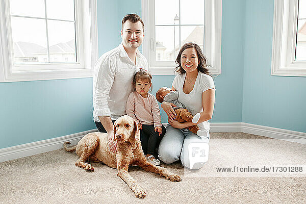 Happy multiracial young family with newborn and toddler kids at home.