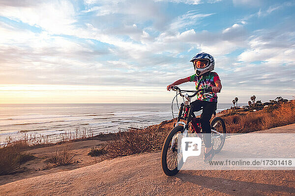 Kleiner Junge fährt mit dem Fahrrad auf einem Küstenweg