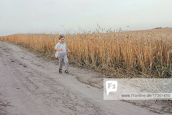 Portrait of a happy 5 years little cute boy  wearing white shirt running in the wheat field