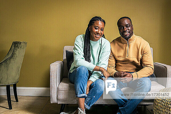 Porträt eines lächelnden reifen Paares  das zu Hause auf dem Sofa sitzt