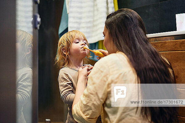 Eine Mutter bringt ihrem Sohn das Zähneputzen bei. Im Badezimmer.