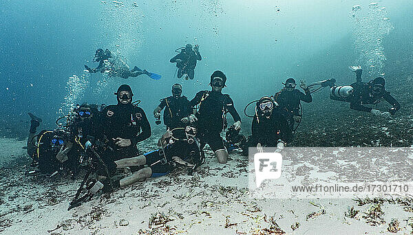 Eine Gruppe von Freunden posiert für die Kamera auf dem Meeresboden in Raja Ampat