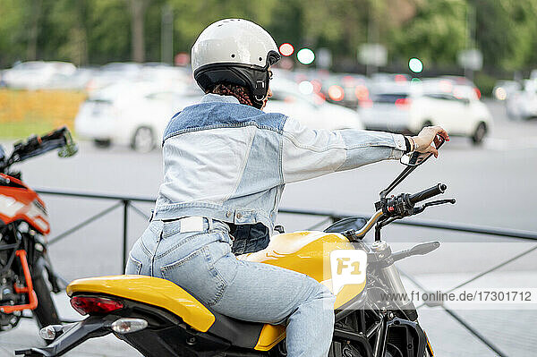 Aufnahme einer jungen Frau auf einem gelben Motorrad von hinten rechts