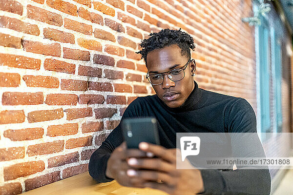 junger afrikanischer Mann arbeitet mit seinem Smartphone