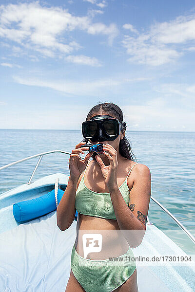 Young woman preparing to snorkel in ocean