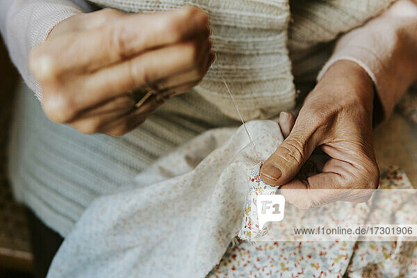 Close up shot of woman's hands sewing with needle and thread