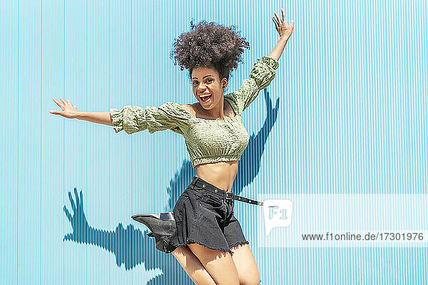 glückliche Frau mit Afro-Haar  die vor Freude springt