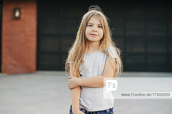 Close up of a young girl standing outside in front of garage door