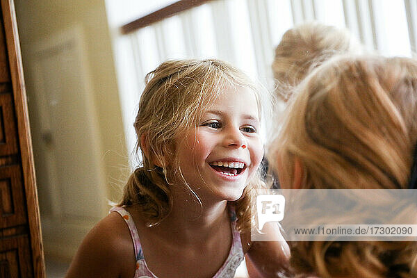 kleines Mädchen lacht beim Blick in den Spiegel