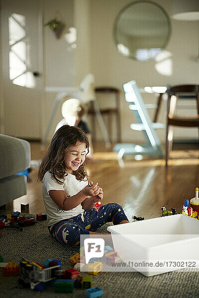 Cute girl smiling while playing with toys at home