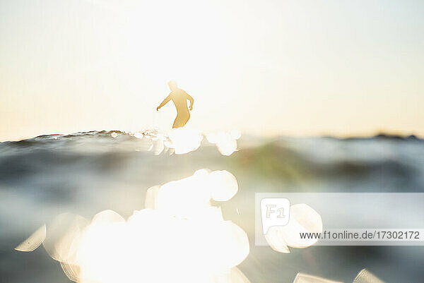 Gegenlicht Mann Surfen auf einer Welle im Sommer Sonnenuntergang