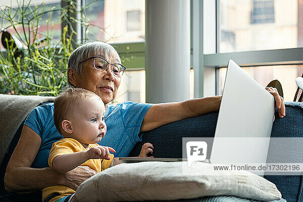 Älterer Großelternteil und Enkelin schauen gemeinsam auf den Computer