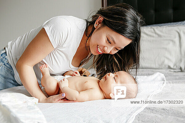 Feiertag Muttertag. Glückliche chinesische asiatische Mutter schaut auf neugeborenen Sohn