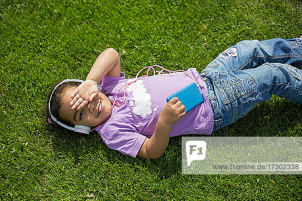 glückliches Latina-Mädchen mit Smartphone und Helm auf dem Sportplatz