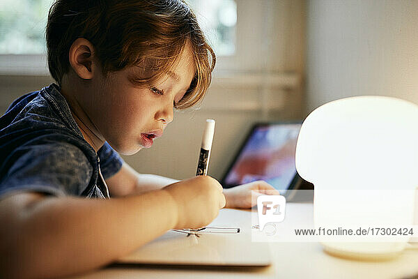 Konzentrierter Junge beim Zeichnen mit Filzstift zu Hause