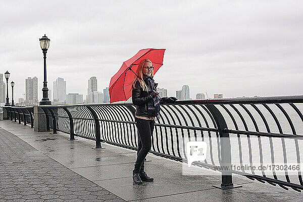 Frau mit Regenschirm auf der Stadtpromenade an einem düsteren Tag