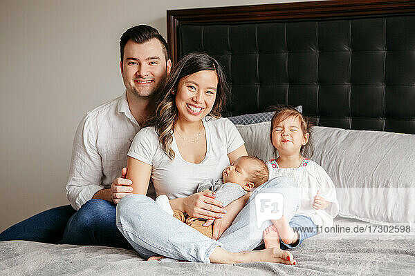 Happy funny family with two little kids toddler and newborn at home
