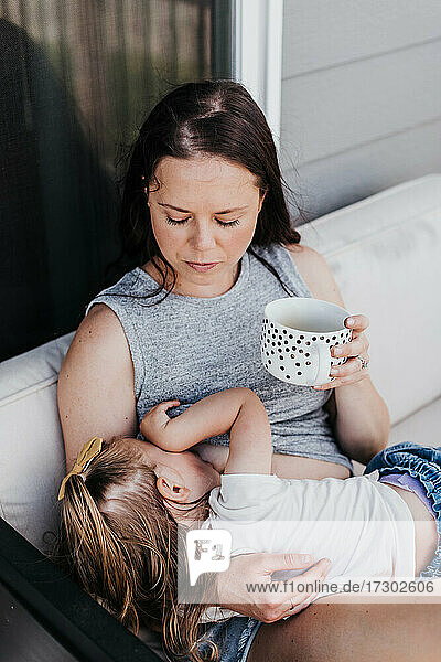 Mutter stillt Kleinkind an einem Sommertag auf ihrer Veranda