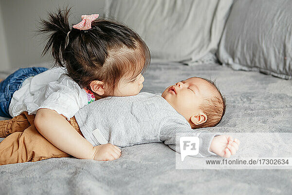 Cute Kleinkind ältere Schwester umarmt neugeborenen jüngeren Baby Bruder Junge.