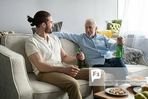 Enkel hört dem Großvater auf dem Sofa zu