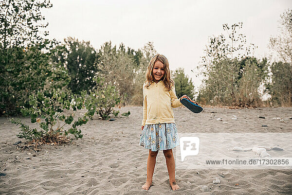 Young girl smiling in the sand on a beach by the Yellowstone River