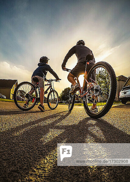 Wide angle shot of father and child going on an evening bike ride.