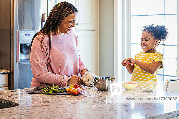 Fröhliche Tochter hilft der Mutter bei der Zubereitung von Essen zu Hause