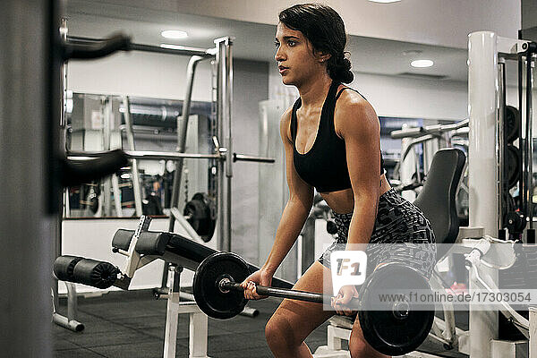Junge Frau hebt Gewichte in einem Fitnessstudio