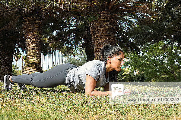 junges Mädchen trainiert Bauchmuskeln auf dem Rasen im Park