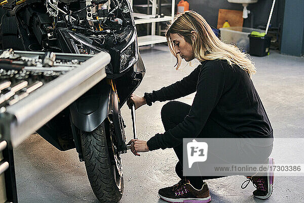 Mechanic woman works in a garage repairing a motorcycle