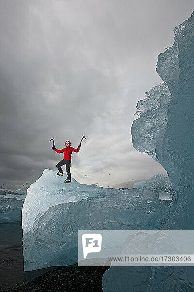 Frau klettert mit Eispickel auf Eisberg an der Südküste von Island