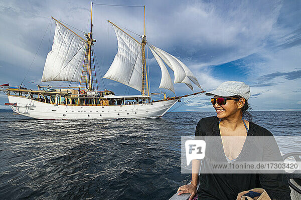Frau nähert sich Segelboot auf Beiboot in Raja Ampat