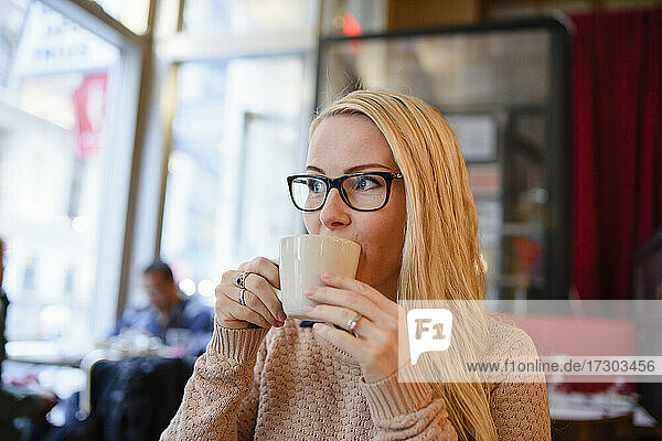 Pensive woman drinking coffee in cafe