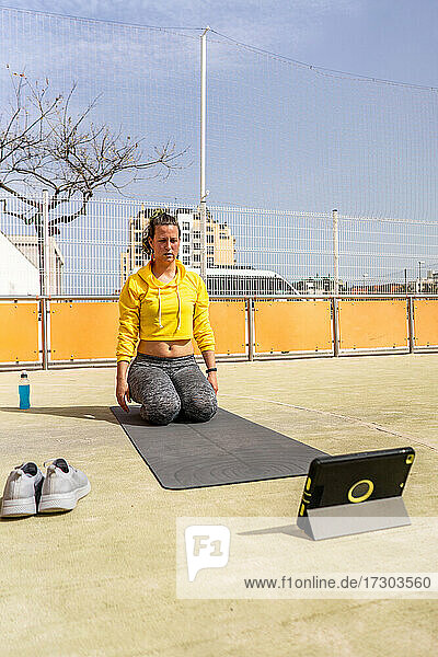 Aktive Frau während einer Online-Yoga-Sitzung mit Tablet im Sportbereich