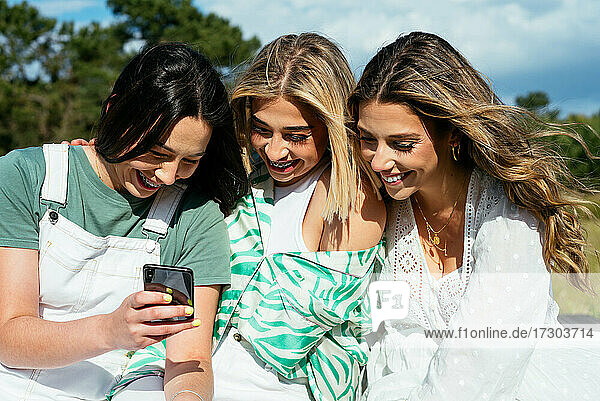 Drei Freundinnen benutzen ein Mobiltelefon und haben Spaß