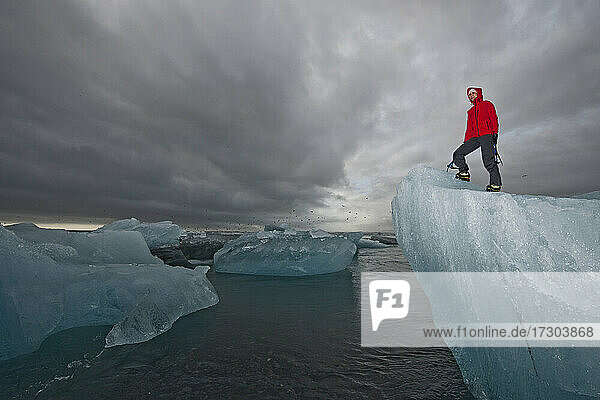 Frau klettert mit Eispickel auf Eisberg an der Südküste von Island