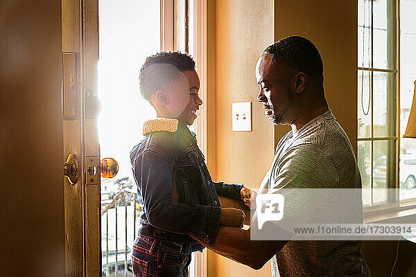 Seitenansicht eines lächelnden Sohnes mit seinem Vater am Eingang des Hauses