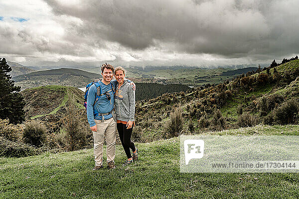 Active middle aged couple in New Zealand standing with mountains in background