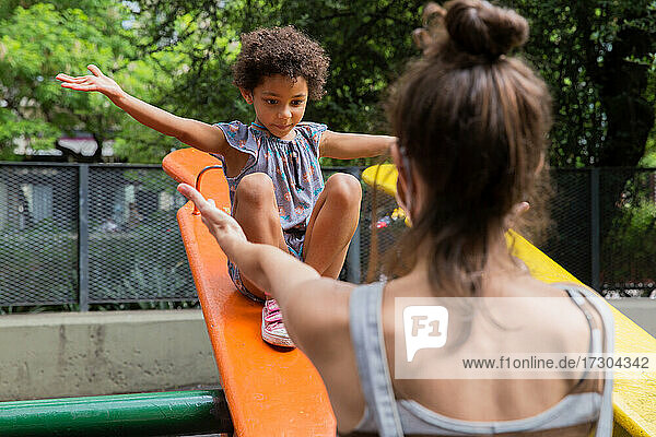 Gemischtrassiges Mädchen genießt ihre Mutter auf dem Spielplatz im Freien