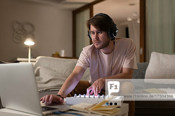 Männlicher DJ  der zu Hause am Laptop Musik mischt