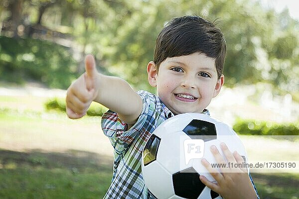 Netter kleiner Junge spielt mit Fußball im Freien im Park