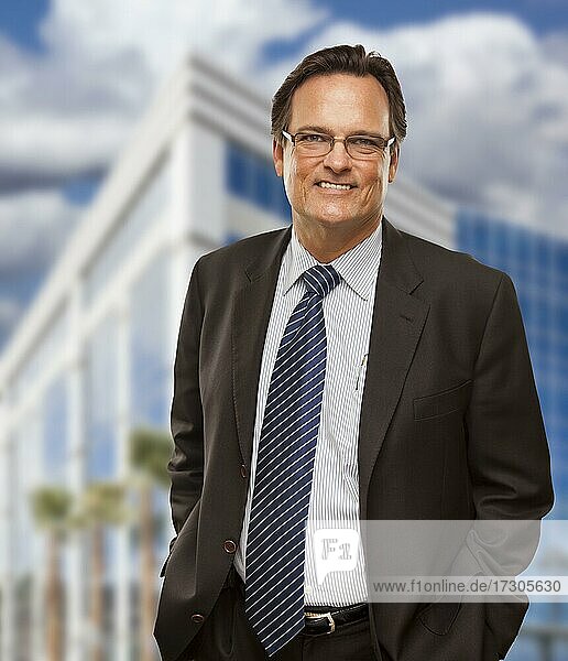 Handsome businessman in suit and tie smiling outside of corporate building