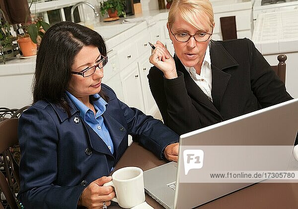 Businesswomen working on the laptop together in the kitchen