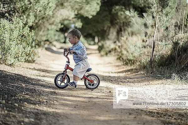 Cute toddler riding his bicycle on the dirt road