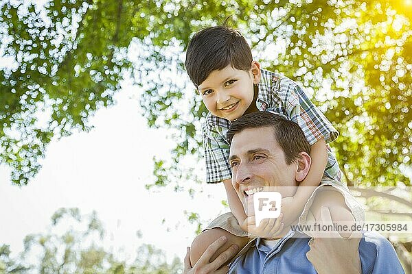 Gemischtrassiger Vater und Sohn spielen zusammen Huckepack im Park